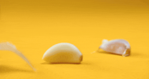 Dente de alho a cair sobre fundo amarelo